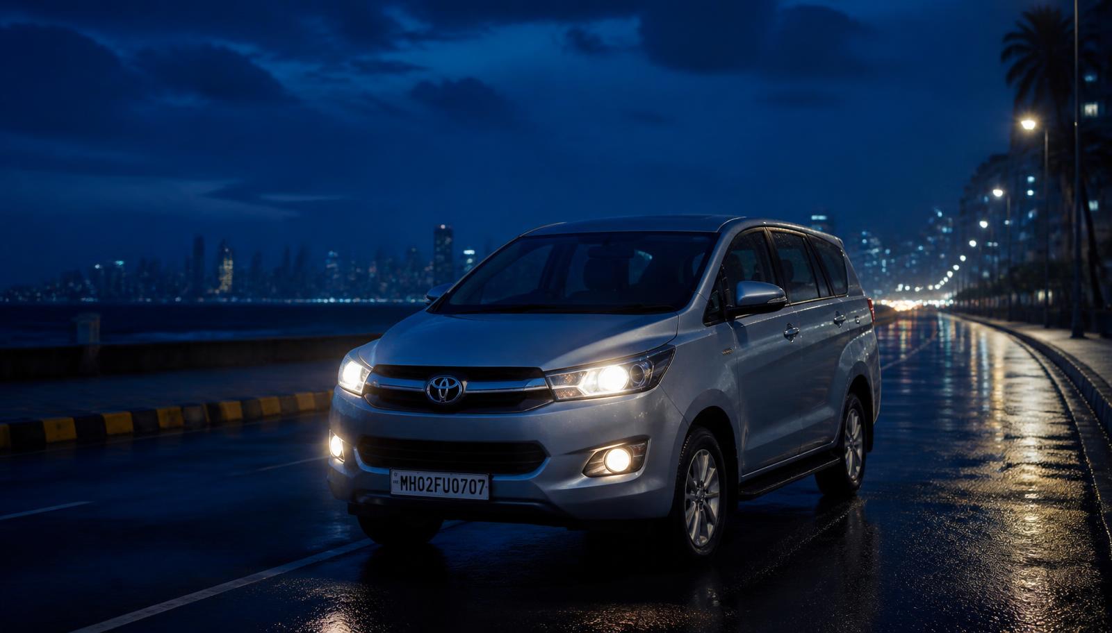 Silver 7-seater MPV on a calm Mumbai seafront road at dusk